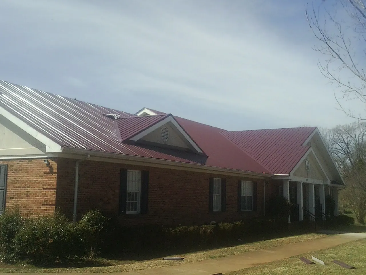 Red metal roof with gabled entries on a long brick building in Broadalbin