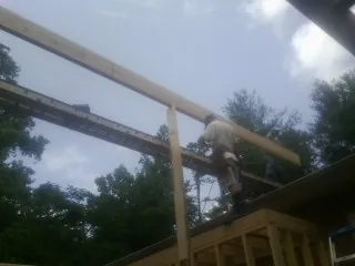 Carpenter setting a ridge beam over a new addition frame — Ice Dam Removal by Roofing Brothers in Broadalbin