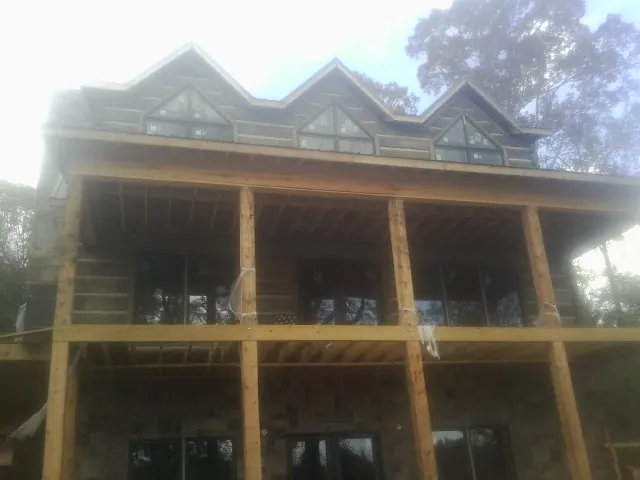 Dormers and porch framing on a large log home under construction — Roof Coating work by our crew in Broadalbin