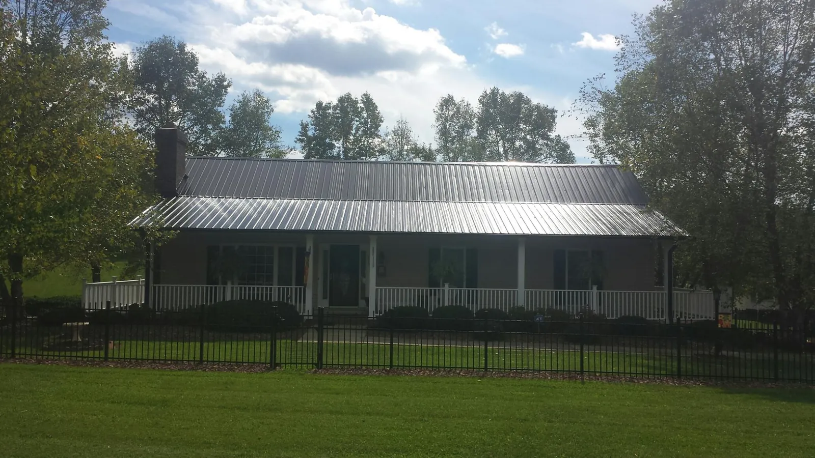 Gray metal roof on a brick ranch with a full width front porch — Gutter Guard Installation work by our crew in Broadalbin