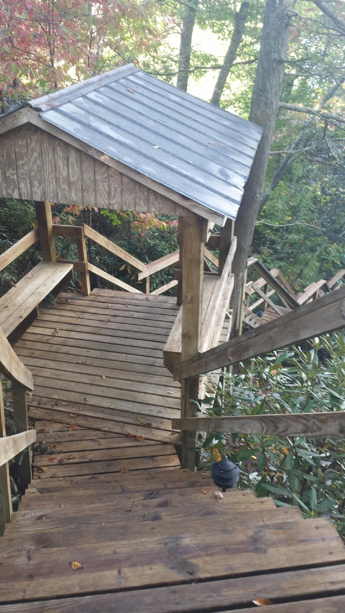 Metal roofed shelter over wooden steps on a wooded walkway — Skylight Repair & Installation work by our crew in Broadalbin
