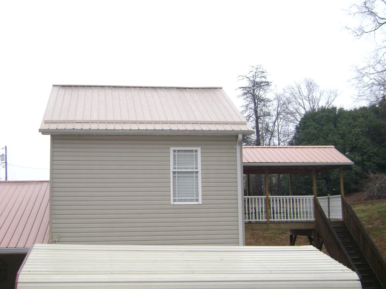 Tan metal roofs on a two story addition and attached porch, from a Roof Replacement job in Broadalbin