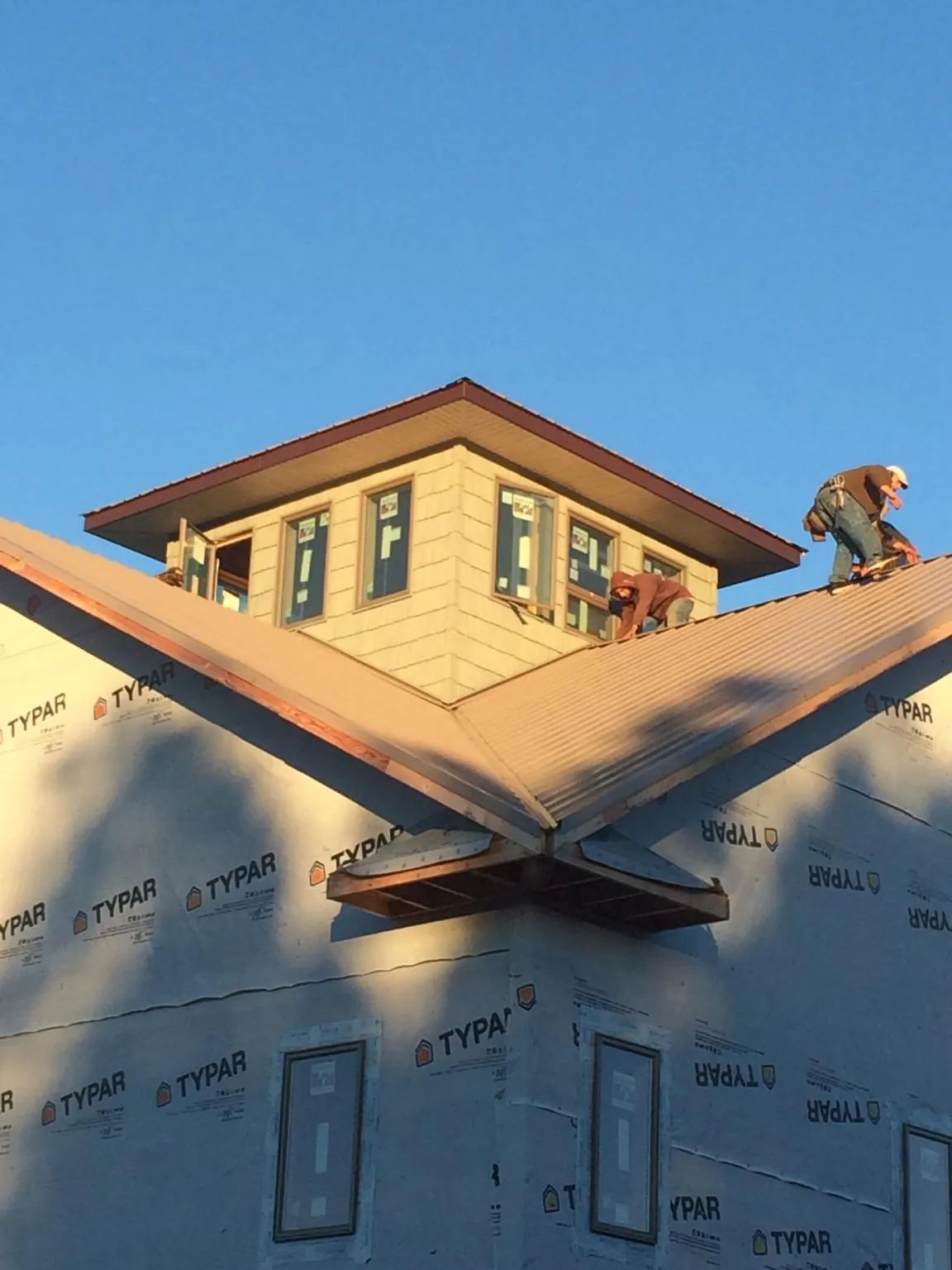 Roofers working around a rooftop cupola on a new metal roof at sunset — Roof Waterproofing in Broadalbin by Roofing Brothers